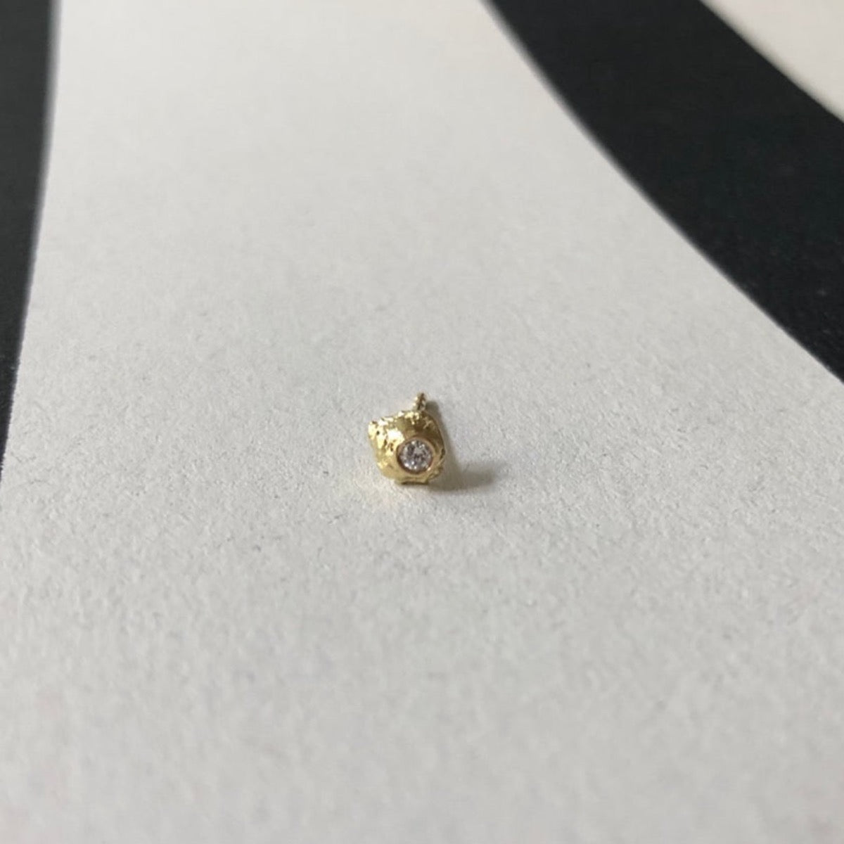 Lava diamond earring. 18 kt recycled gold and a  0.03ct Diamond